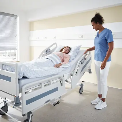 El cuidador ajusta las barandillas de seguridad de la cama de hospital Evario one.