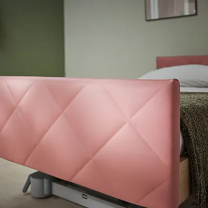 Elvido Pflegebett mit gepolstertem Fußteil in Rautensteppung aus Stoff oder Kunstleder.