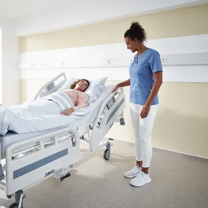 Caregiver adjusts safety sides of Evario one hospital bed