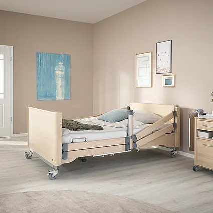 Arena heavy-duty care bed with split safety sides and raised backrest for safe mobilisation.