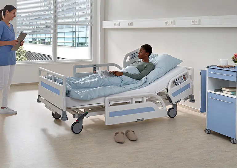 Lit hospitalier Evario one avec système de protection latérale 3/4 à barreaux continus pour une mobilisation sûre et le confort du patient.