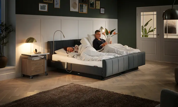 Ältere Frau liest im Libra deluxe Komfortbett von Stiegelmeyer in modern eingerichteter Umgebung“