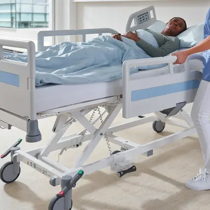 Pielęgniarka podnosi barierkę boczną łóżka szpitalnego Evario one.