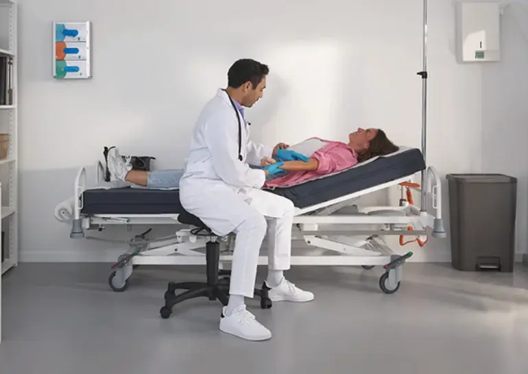 Lit hospitalier Evario one présenté sans système de protection latérale pour un accès sans entrave au patient et des soins flexibles.