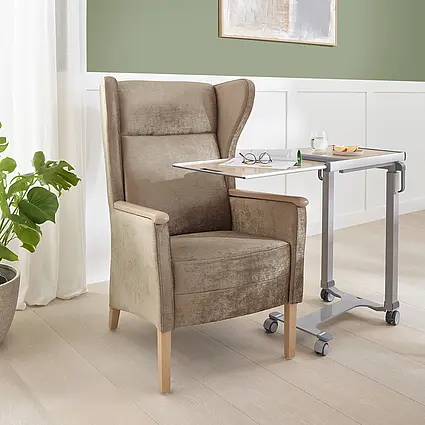 Sillón Luna de respaldo alto con mesa auxiliar y bebida en una moderna habitación de cuidados