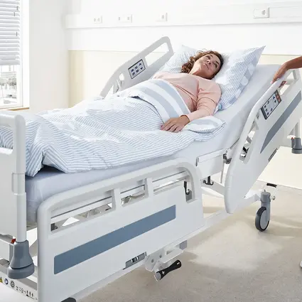 Pielęgniarka ustawia zabezpieczenie boczne łóżka szpitalnego Evario one.