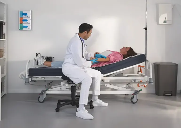 Lit hospitalier Evario one présenté sans système de protection latérale pour un accès sans entrave au patient et des soins flexibles.