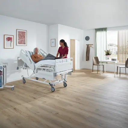 O cuidador ajusta as barras de segurança da cama hospitalar Evario one