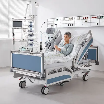 Patient im Sicuro tera Krankenhausbett mit hochgestellter Rückenlehne im Patientenzimmer