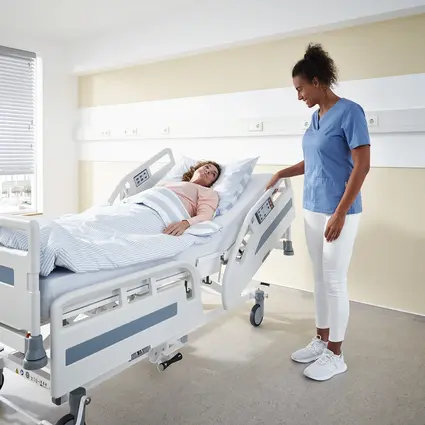 O cuidador ajusta as grades de segurança da cama hospitalar Evario one