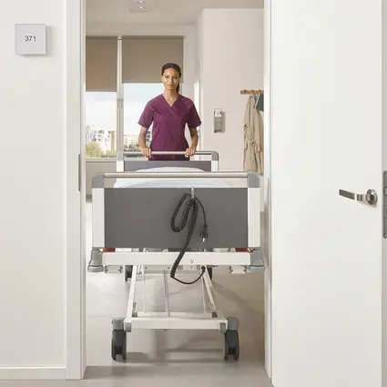 Caregiver pushes narrow Evario one bed with a width of 89 cm through door