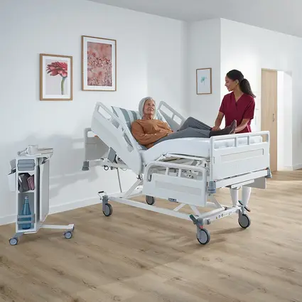 Patientin im Evario one, Pflegekraft passt Arbeitshöhe ergonomisch an