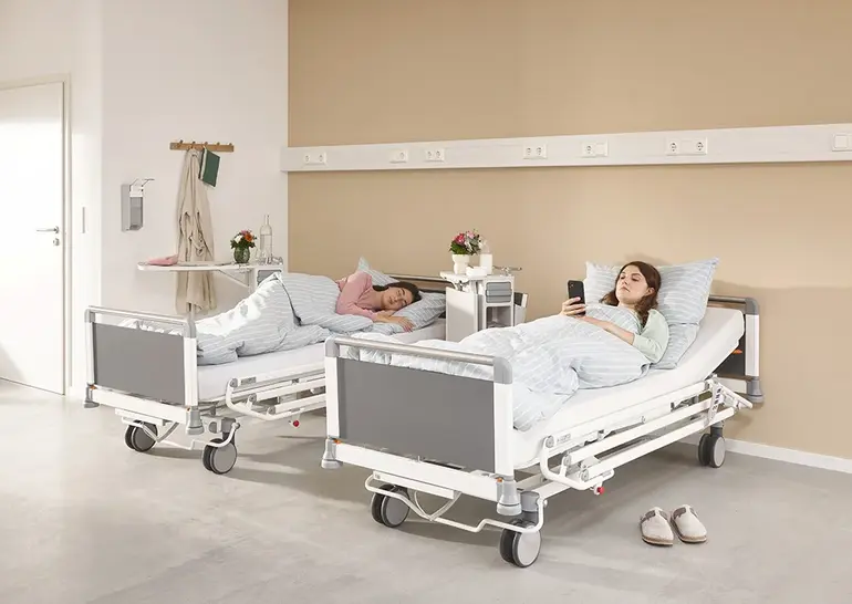 Lit hospitalier Evario one équipé d’un système de protection latérale 3/4 pivotant pour un fonctionnement ergonomique et la sécurité du patient.