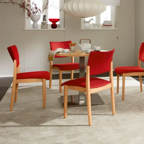 Fena-Stuhlserie ohne Griffbügel mit gepolsterter Sitzfläche und Rückenlehne – vier Stühle um einen Tisch in wohnlichem Aufenthaltsraum