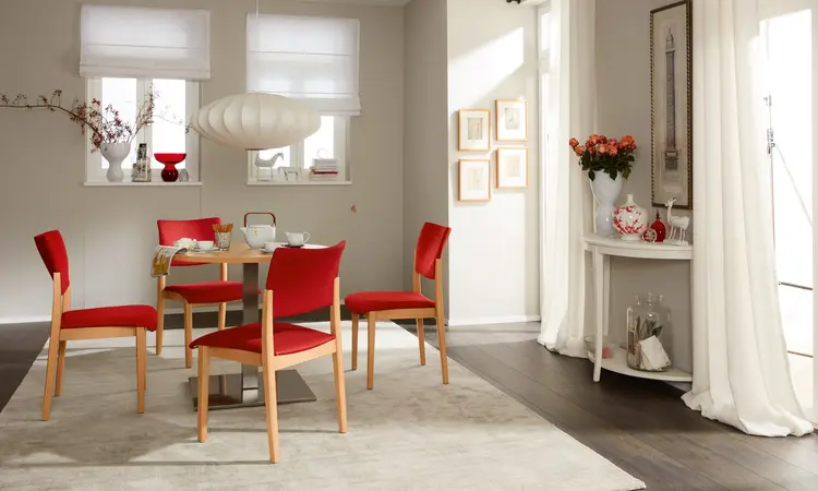 Fena-Stuhlserie ohne Griffbügel mit gepolsterter Sitzfläche und Rückenlehne – vier Stühle um einen Tisch in wohnlichem Aufenthaltsraum