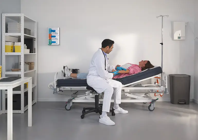 Cama de hospital Evario one mostrada sin laterales de seguridad para un acceso sin obstáculos del paciente y una atención flexible.