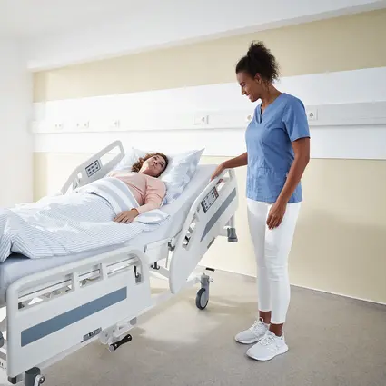 Le soignant ajuste les systèmes de protection latérale du lit d'hôpital Evario one.