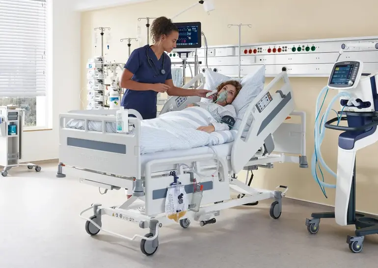 Dans une chambre d’hôpital équipée d’un lit et de matériel médical, une infirmière prend la température d’une patiente.