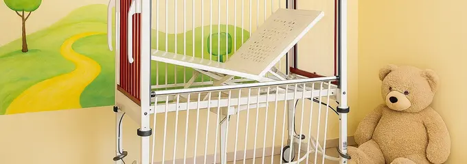 En un boceto generado con IA, la cama infantil con cabecero y piecero rojos se encuentra delante de una pared amarilla con un motivo paisajístico pintado. En el suelo, junto a la cama, hay un gran oso de peluche.