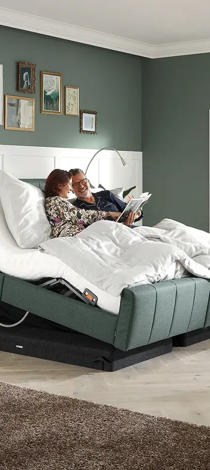 La cama Libra - variante deluxe se muestra como cama doble mostrando a una pareja en una cómoda posición sentada.