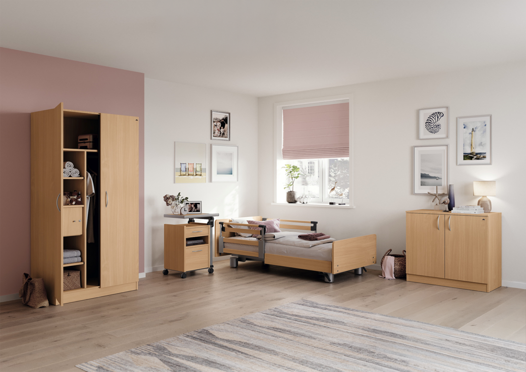 Patientenzimmer im Wohlfühlambiente in Holz und soft Natural-Design. Zu sehen ist aus dem Adrano Programm ein Kleiderschrank und Anrichte mit jeweils zwei Türen in Holzoptik. Ebenfalls zu sehen, das Niedrigbett Libra und Aparto (B3) Nachttisch.