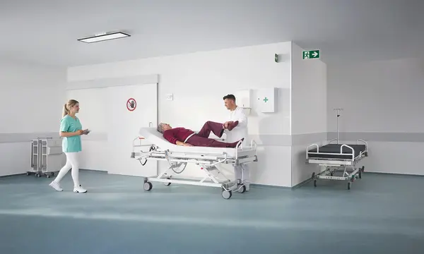 Evario one hospital bed in a modern outpatient clinic with medical equipment, designed for safe and flexible patient care.