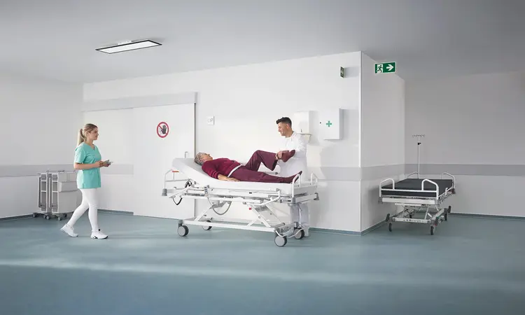 Evario one hospital bed in a modern outpatient clinic with medical equipment, designed for safe and flexible patient care.