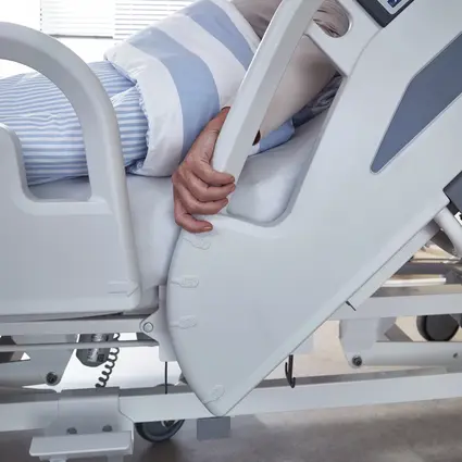 Patiënt reikt naar verhoogde veiligheidszijkanten met hoekindicator op de Evario one