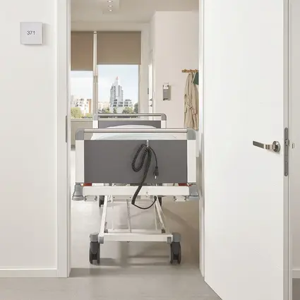 Opiekunka przepycha przez drzwi wąskie łóżko Evario one o szerokości 89 cm