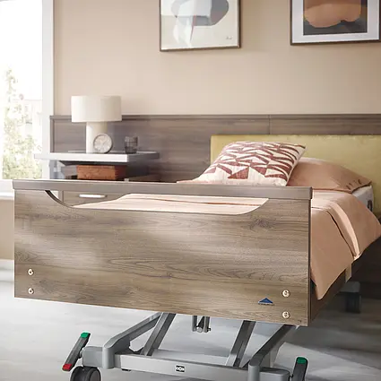 Elvido Pflegebett mit wohnlichem Kopf- und Fußteil in Holzdekor, optional mit Griffleiste.