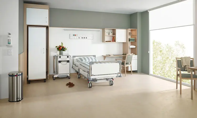 Krankenhausbett Puro von Stiegelmeyer in modernem Wahlleistungszimmer mit Nachttisch, Schrank, Schreibtisch und Sitzbereich am Fenster