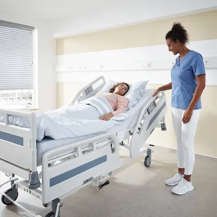 Caregiver adjusts safety sides of Evario one hospital bed