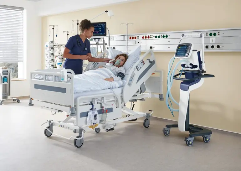 In a hospital room equipped with a bed and medical equipment, a nurse takes a patient's temperature.