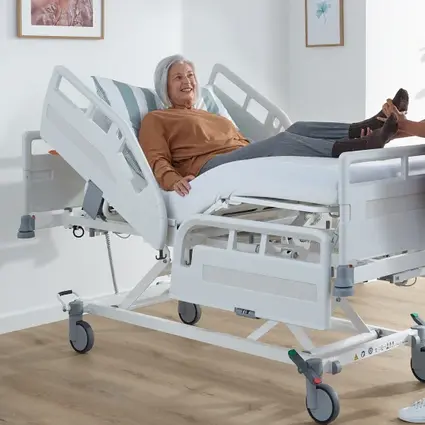 Pacjentka siedzi w łóżku szpitalnym na idealnej wysokości roboczej dla pielęgniarki.