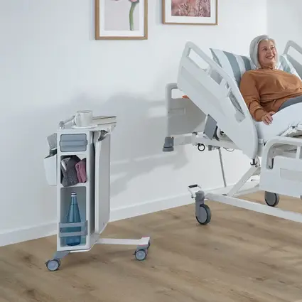 Pacjentka siedzi w łóżku szpitalnym na idealnej wysokości roboczej dla pielęgniarki.