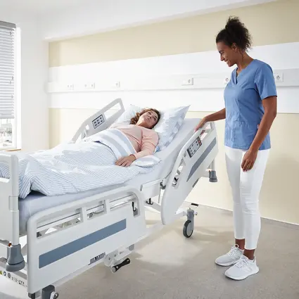 Pflegekraft stellt Seitensicherung des Evario one Krankenhausbetts ein